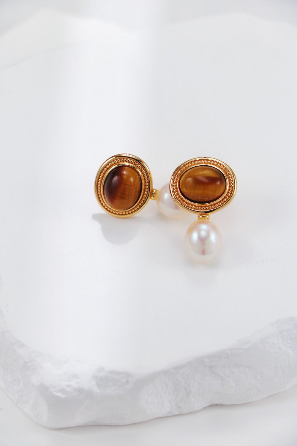 surrounded by delicate crafted gold there is a oval shape tiger eye stone, and a dangle pearl below. vintage french style 