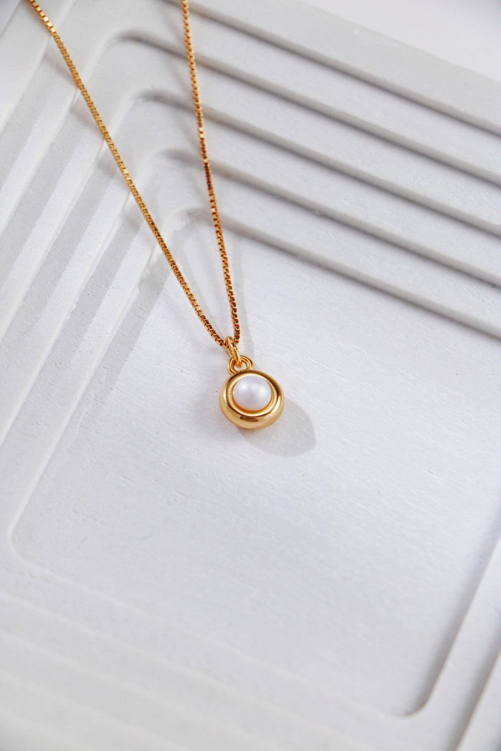 a natural pearl surrounded by a gold circle, with a simple chain, giving a minimalist style to your everyday look. it's medium length is perfect for wear it solo and layering.