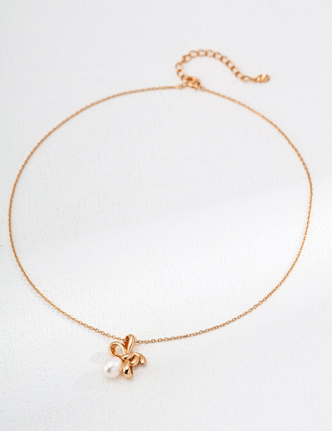 a gold bow-tie with a natural pearl on it, short adjustable necklace, perfect for layering and styling