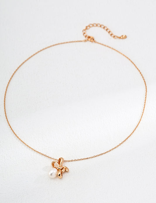 a gold bow-tie with a natural pearl on it, short adjustable necklace, perfect for layering and styling